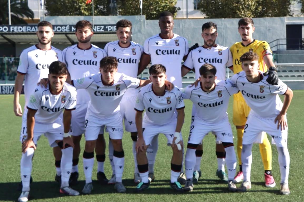Once jugadores de fútbol posan en dos filas sobre el césped, diez con camiseta blanca con la palabra Ceuta y uno con amarilla.